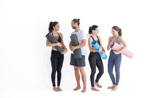 Group of happy sporty girls and guy wearing body stylish sportswear holding personal carpets leaned on a white background. waiting for yoga class or body weight class. healthy lifestyle and wellness photo