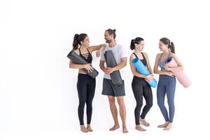 Group of happy sporty girls and guy wearing body stylish sportswear holding personal carpets leaned on a white background. waiting for yoga class or body weight class. healthy lifestyle and wellness photo