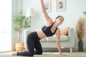 cerca arriba mujer confidente formación yoga. atlético mujer en ropa de deporte haciendo aptitud extensión ejercicios a hogar en el vivo habitación. deporte y recreación concepto. yoga profesor es Ayudar muchacha. foto