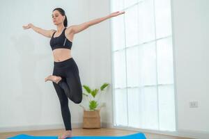 dos mujer confidente formación yoga. atlético mujer en ropa de deporte haciendo aptitud extensión ejercicios a hogar en el vivo habitación. deporte y recreación concepto. yoga profesor es Ayudar joven mujer. foto