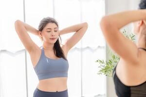 cerca arriba mujer confidente formación yoga. atlético mujer en ropa de deporte haciendo aptitud extensión ejercicios a hogar en el vivo habitación. deporte y recreación concepto. yoga profesor es Ayudar muchacha. foto