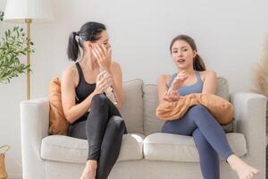 Group of happy sporty women wearing body stylish sportswear and talking together. waiting for yoga class.. healthy lifestyle and wellness. Couple women are relaxing and sitting at sofa in living room. photo