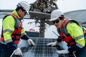 engineer men inspect modules of photovoltaic cell panels. Industrial Renewable energy of green power. workers prepare materials before construction on site with the stack of panels at background. photo