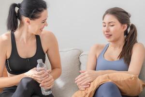 Group of happy sporty women wearing body stylish sportswear and talking together. waiting for yoga class.. healthy lifestyle and wellness. Couple women are relaxing and sitting at sofa in living room. photo