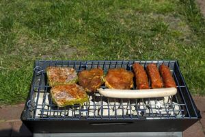 el salchichas y carne en parrilla. verano picnic exterior. foto