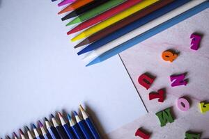 multicolor letras y conjunto de lapices en el mesa. vistoso de madera alfabeto y lapices en un mesa. foto