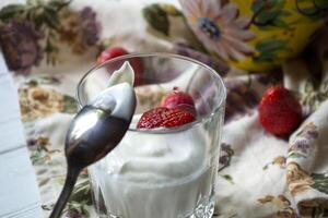 Ripe strawberries and glass of cream on a white wooden table. The healthy food. photo