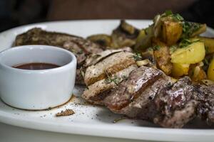 The meat and fried potatoes with sauce on the white plate. photo