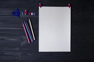 blanco papel, vistoso lapices y decoración en un azul de madera antecedentes. saludo tarjeta foto