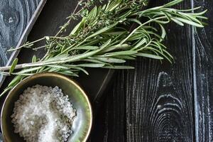 The branches of rosemary, and a white salt on a dark wooden background. photo