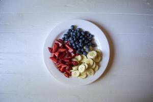 Plate with bananas, strawberries and blueberries. photo