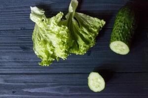 Green vegatables on rustic table. Healthy food. Cucumber and salad on a dark blue wooden background. photo