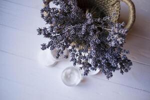 A jar with skin cream and lavender flowers on a white wooden background. photo