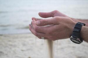 The sand is pouring from male hands. photo