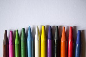 Multicolored pencils on white background. A palette of pencils on a table, close up. photo