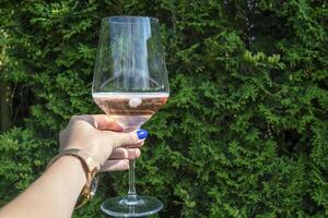 A glass of wine in women's hands against a natural background. Two friends cheering. Drinking wine. photo