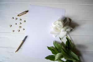 blanco papel, bolígrafo, peonía y decoración en el escritorio. hermosa todavía vida en el escritorio. foto