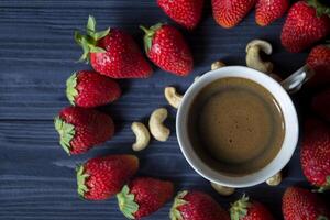 Ripe strawberry, nuts and coffee on a dark blue wooden background. photo