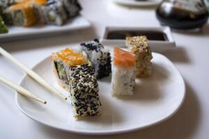 Set of sushi rolls with vasabi and ginger on a white plate. photo