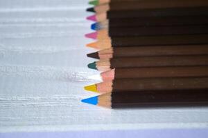 Multicolored pencils on white background. A palette of pencils on a table, close up. photo