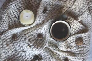 A cup of coffee and woolen scarf with decorations on a table. Coziness. photo