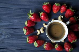Ripe strawberry, nuts and coffee on a dark blue wooden background. photo