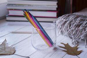 Multicolored pencils in a glass on the desk. photo