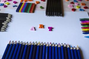 Multicolor letters and set of pencils on the table. Colorful wooden alphabet and pencils on a table. photo