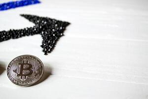 Silver bitcoin with black arrow up on a white wooden background. photo