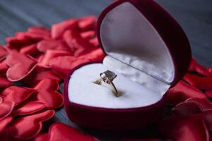 Engagement ring in a red box on a love hearts background. photo