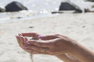 The sand is pouring from woman's hands. photo