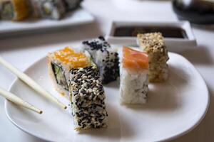 Set of sushi rolls with vasabi and ginger on a white plate. photo