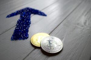 Golden and silver bitcoins with arrows up and down on a white wooden background. photo