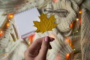 Girl holding autumn leaf. Cozy flat lay. photo