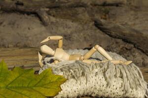 Dummy for drawing in relaxing pose lays on the warm scarf near fallen leaves. Autumn mood. photo