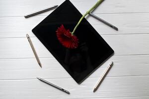 Tablet and active styluses on a white desk, top view. photo