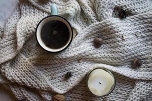 A cup of coffee and woolen scarf with decorations on a table. Coziness. photo