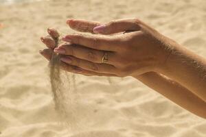 The sand is pouring from woman's hands. photo