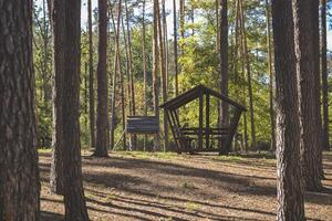 An old wooden pavilion in the forest. Peaceful place for relaxation. photo