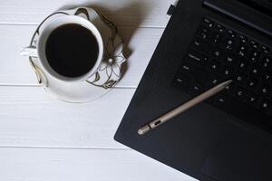 The laptop with active pen, pink mouse and coffee on a white wooden desk. Business flat lay. photo