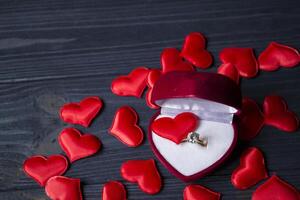 Engagement ring in a red box on a love hearts background. photo