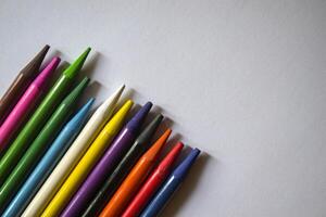 Multicolored pencils on white background. A palette of pencils on a table, close up. photo