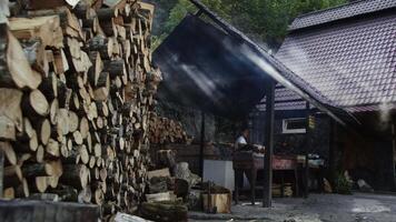 ein Mann Köche Essen auf ein öffnen Feuer, gegen das Hintergrund von ein Stapel von Protokolle video