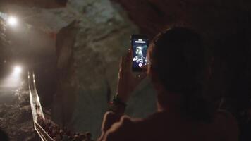 A girl takes pictures of tourists on a bridge in a cave video