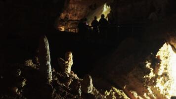 A group of tourists walks past stalagmites on a bridge in a cave video