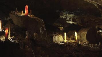 A group of stalagmites are illuminated in a cave video