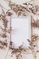 Empty photo frame surrounded by dried flowers on a light background top and vertical view