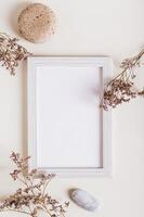 Empty photo frame, dried flowers and stone on a light background top and vertical view