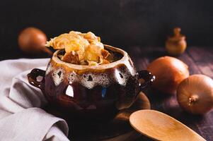 French onion soup with melted cheese and croutons in a pot on the table photo