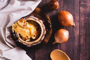 French onion soup with melted cheese and croutons in a pot on the table top view photo